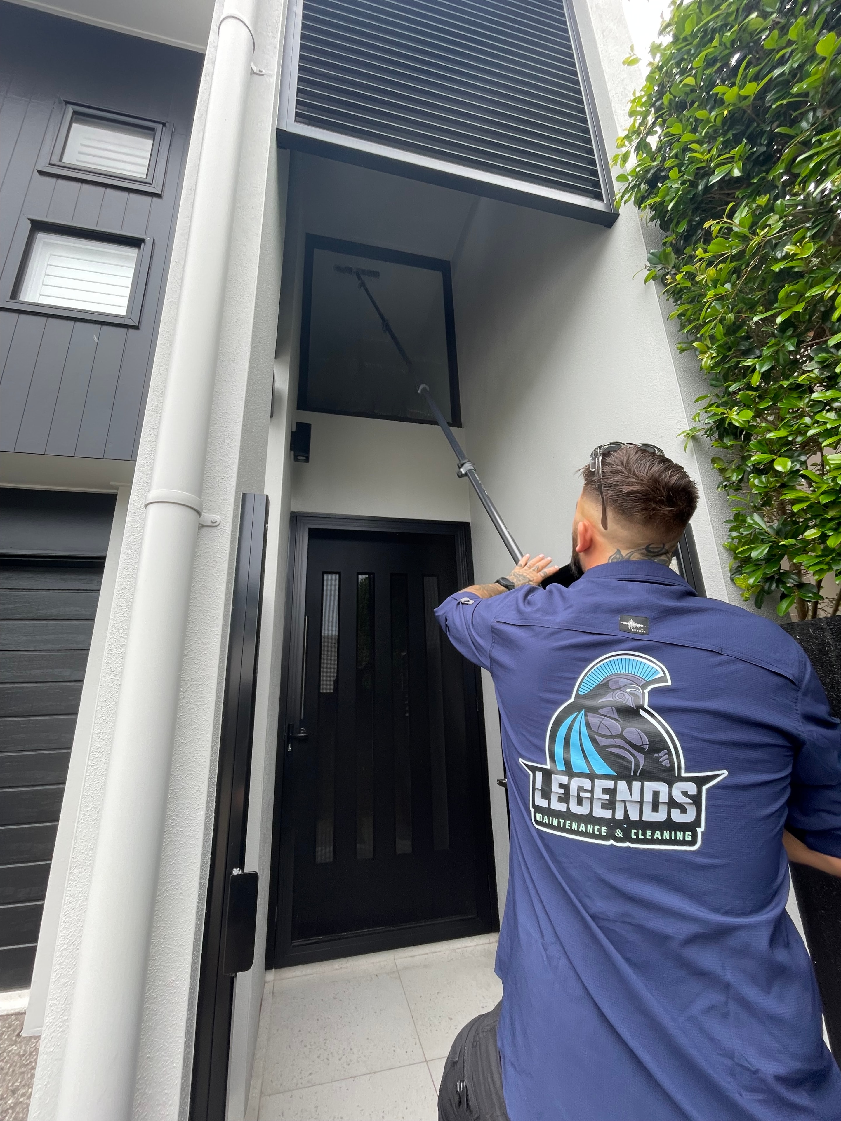 Worker cleaning window with pole brush