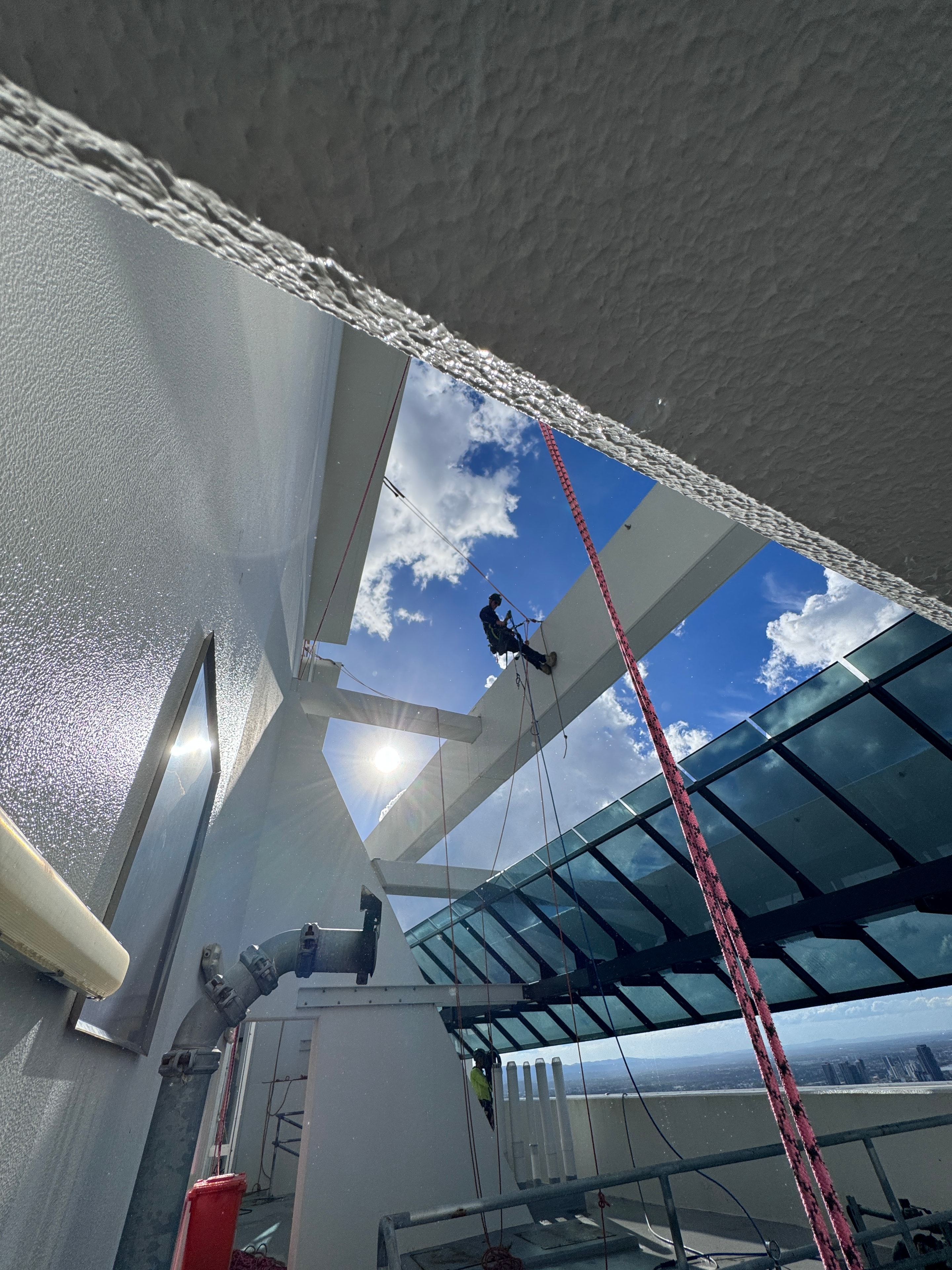 Worker rappelling down modern building exterior