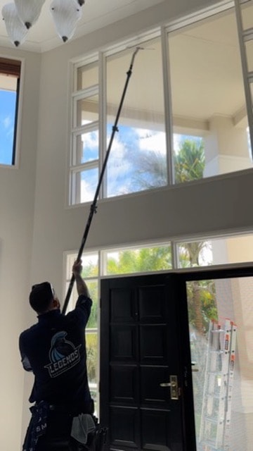 Person cleaning high ceiling windows indoors