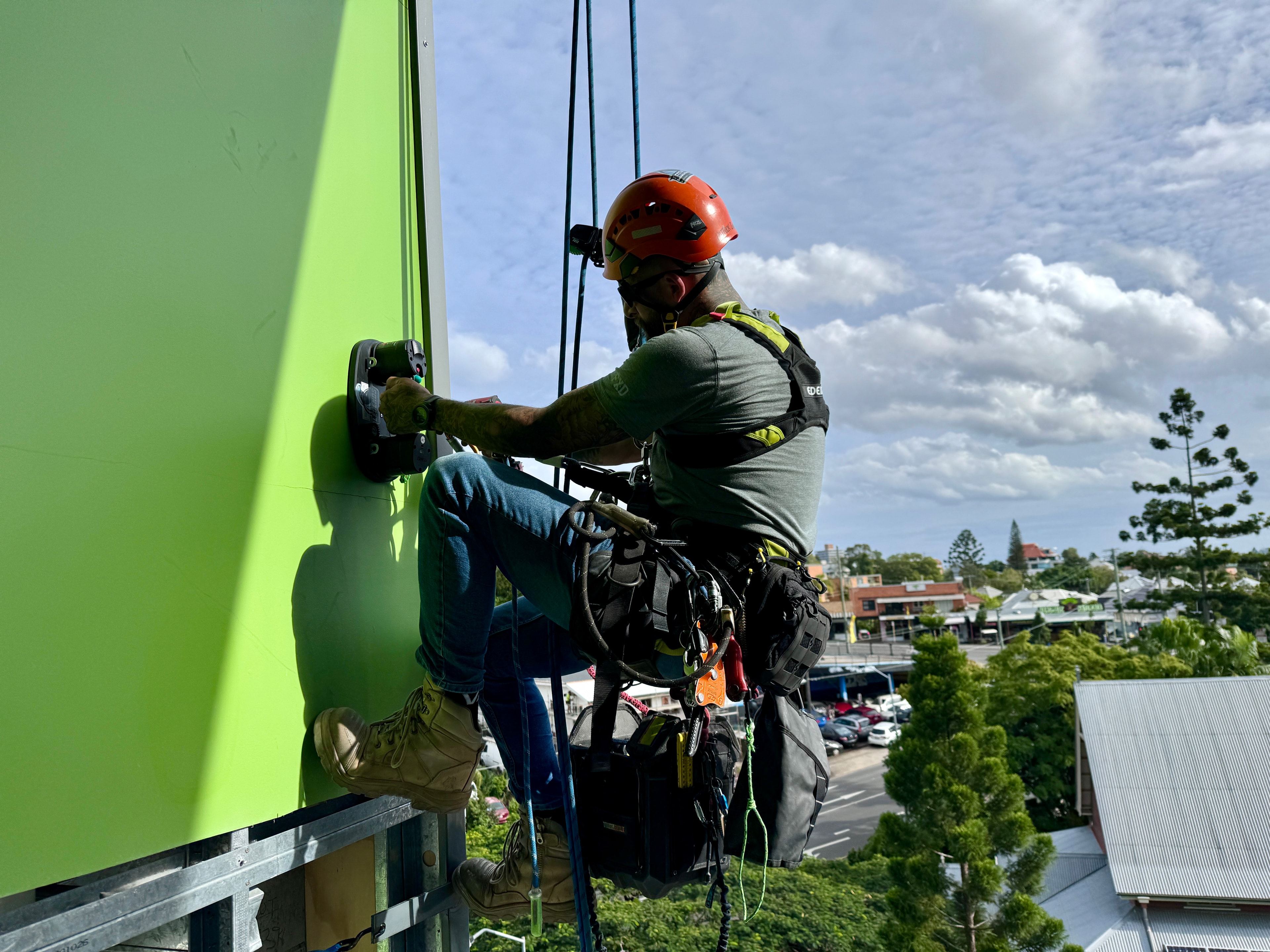 Climber rappelling down bright green wall
