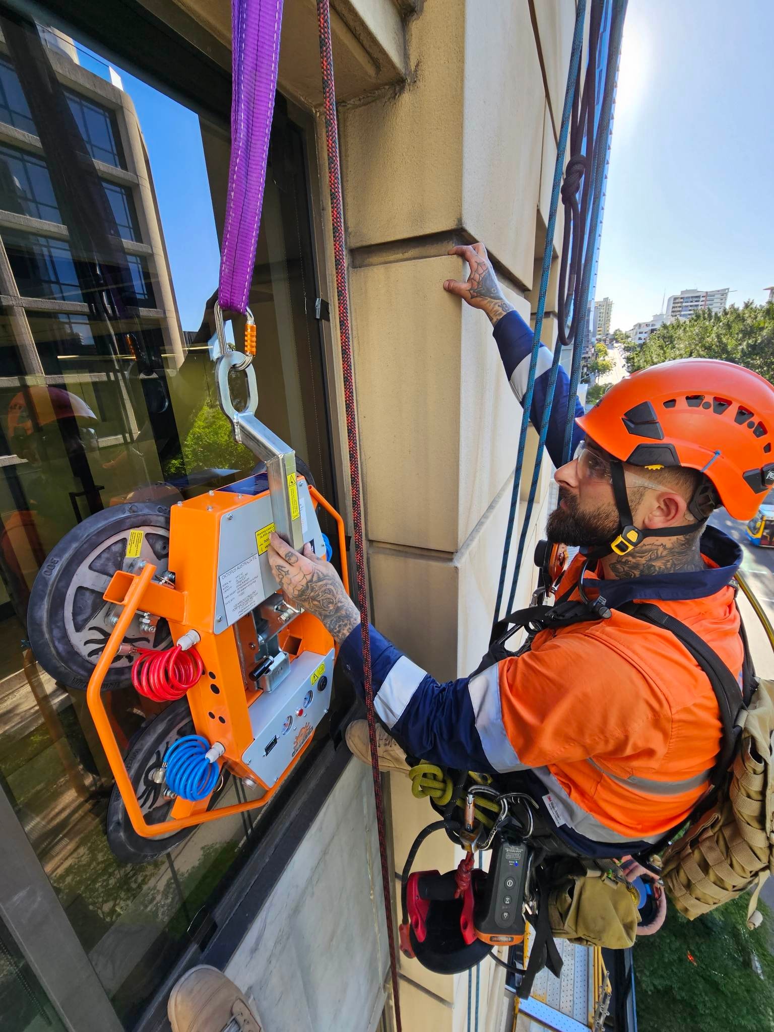 Rope access worker installing equipment on facade