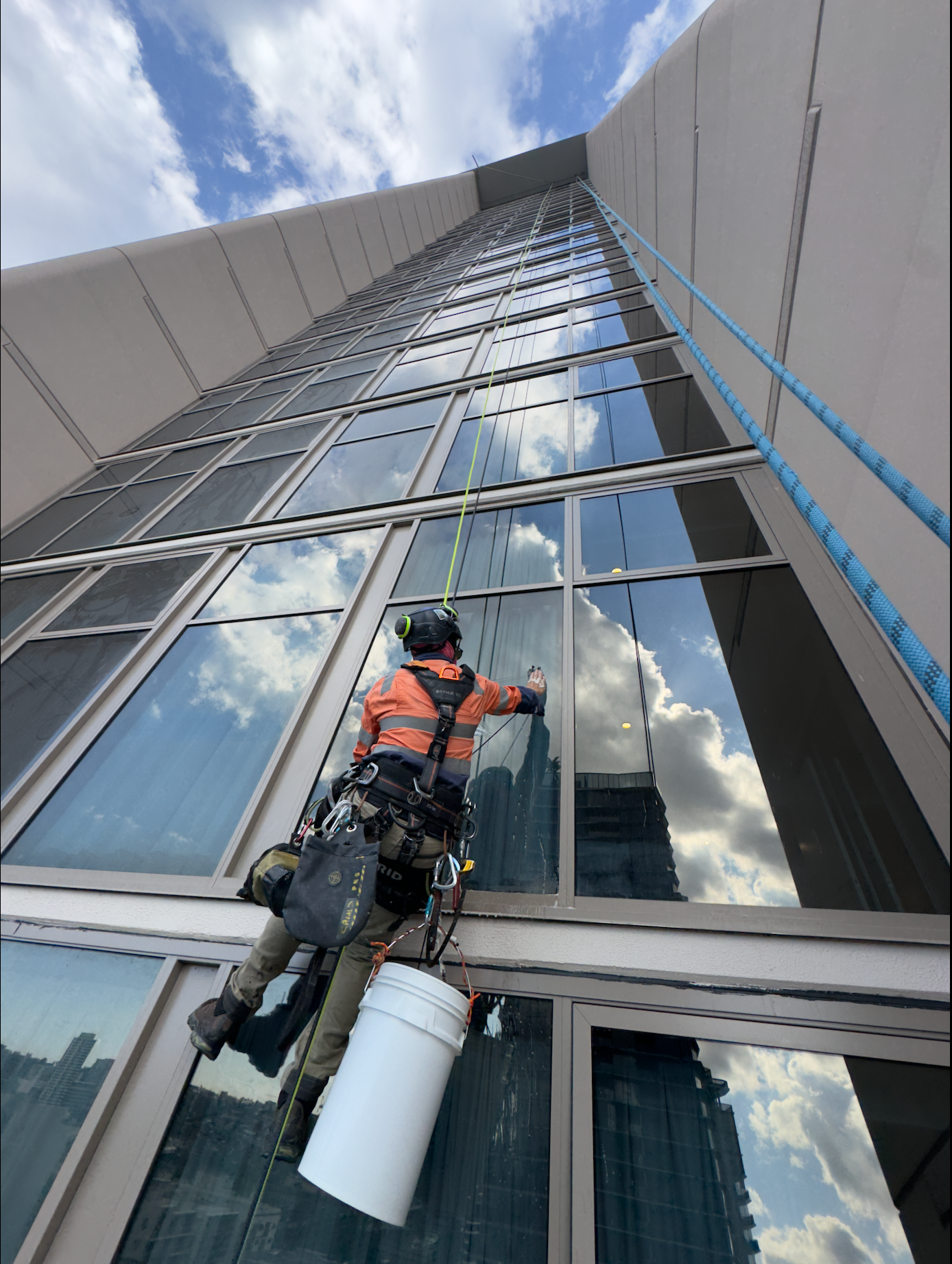 Window cleaner rappelling modern skyscraper facade